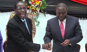 Robert Mugabe shakes hands with Morgan Tsvangirai after signing the new constitution into law (photo credit: Tsvangirayi Mukwazhi/AP)