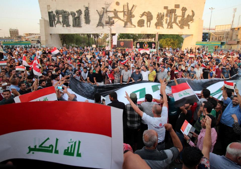 Iraqis wave their national flag during a demonstration against corruption and poor services in Baghdad [photo credit: AFP]