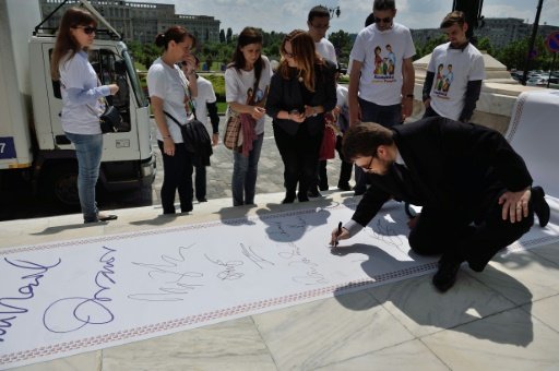 Members of "The Coalition for the Family" symbolically sign as they finish transporting boxes conatining over 3,000,000 signatures to the Romanian Senate (photo credit: AFP)