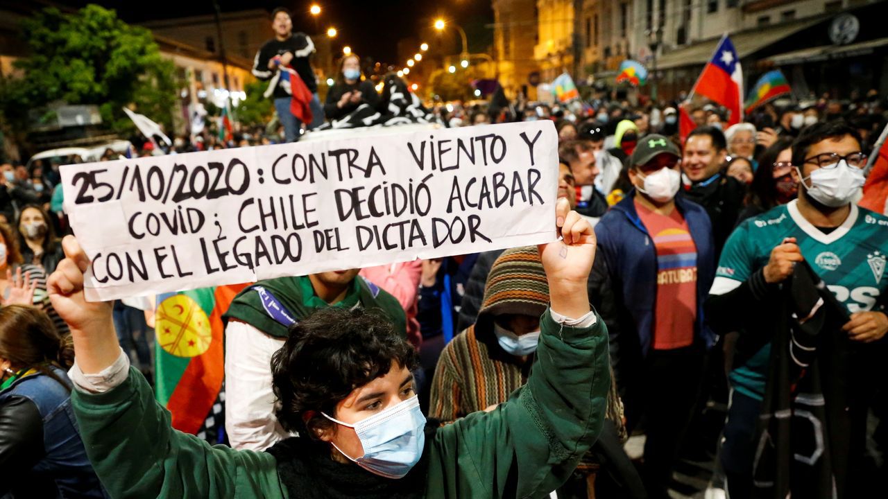 A protester holds a sign with the date of the 2020 national plebiscite on whether to draft a new constitution saying  'Against all odds, Chile decided to end the dictator's legacy' (photo credit: Rodrigo Garrido / Reuters).