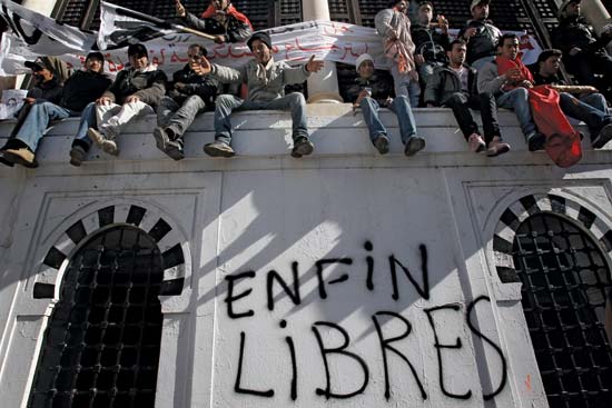 Demonstrators in the capital city of Tunis during the Jasmine revolution sitting on a wall (Photo credit: Christophe Ena/AP)