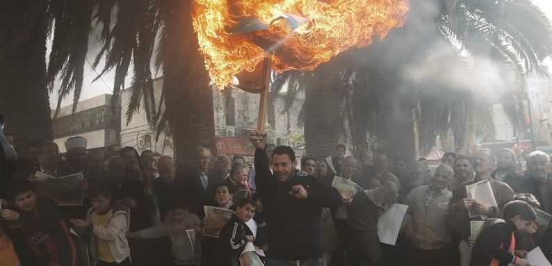 متظاهر فلسطيني يحرق علم «إسرائيل» خلال تظاهرة منددة بمشروع قانون منع الأذان في نابلس/ أ ف ب