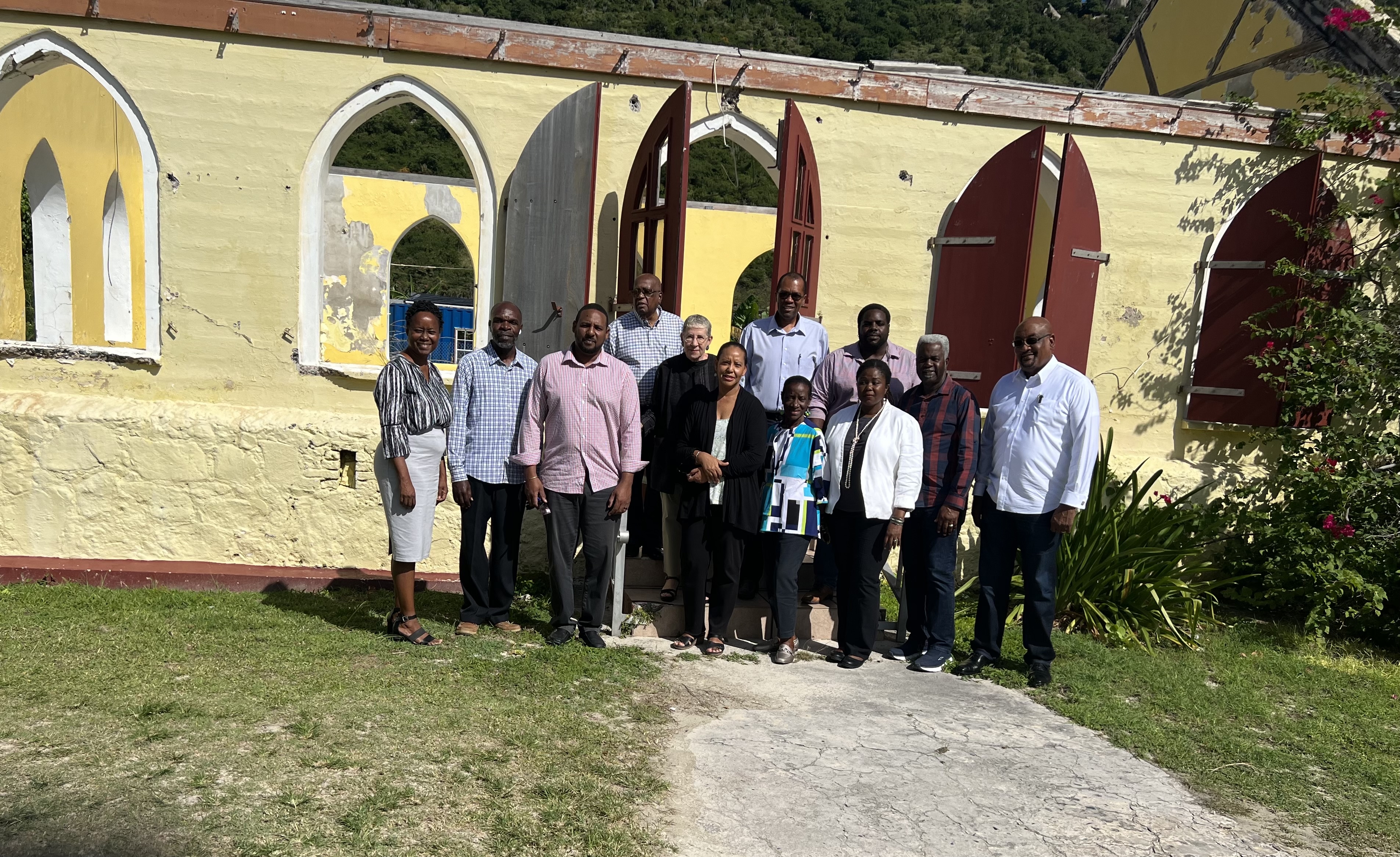 BVI Commission members at a community meeting on the island of Jost Van Dyke stand in front of a church damaged in 2017 by two devastating hurricanes (photo credit: BVI CRC 2022)