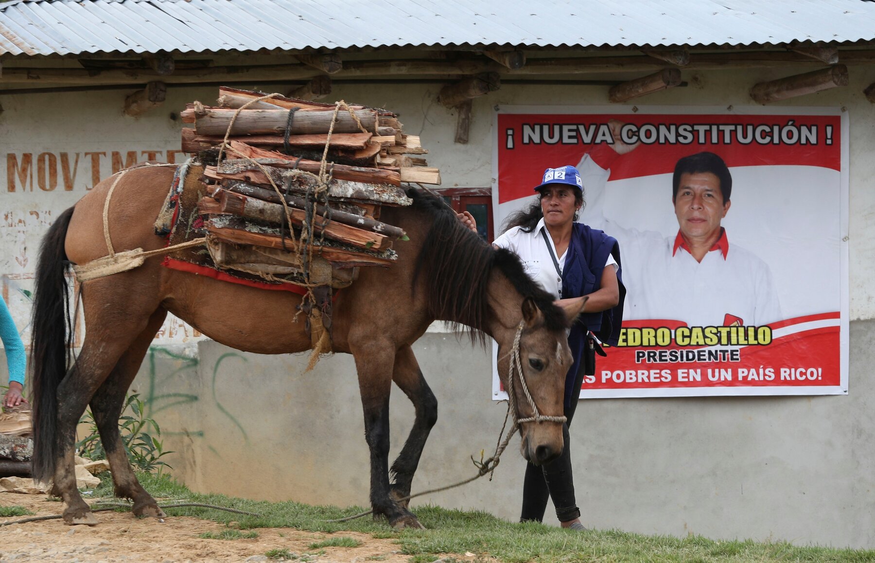 Peruvian in front of Pedro Castillo's election poster promising a new constitution (photo credit: AP / Martin Mejia)