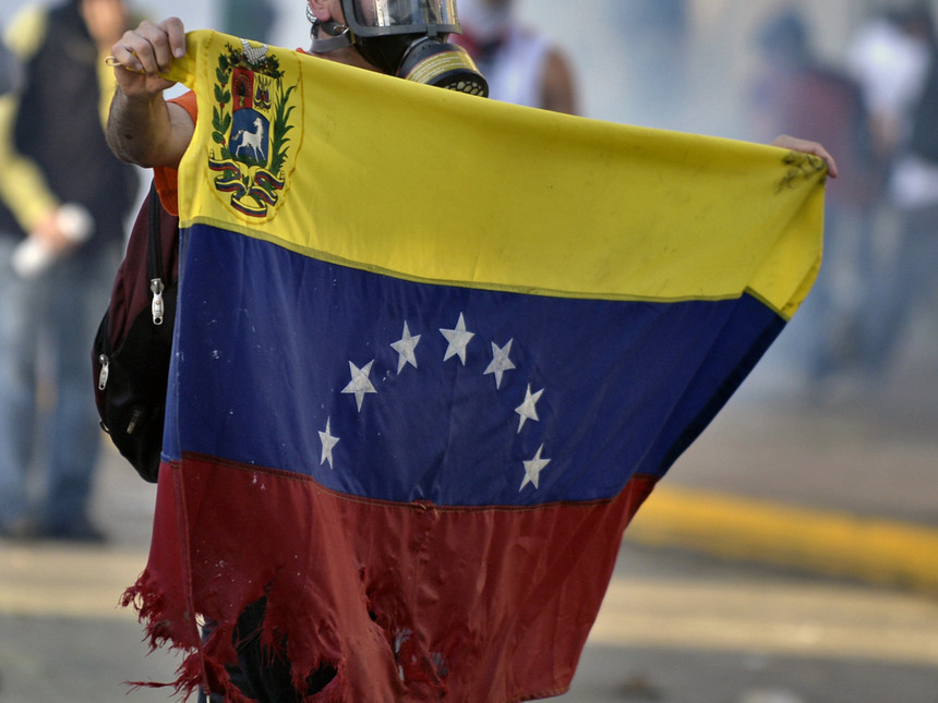 A protester holding Venezuela's flag (Photo credit: wsimag.com)