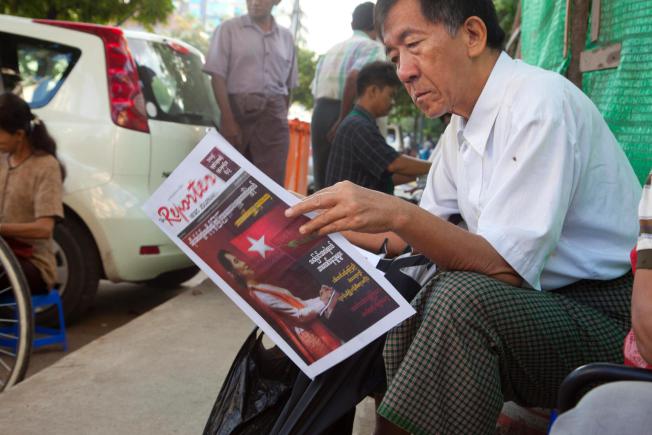 A man reads a newspaper covered with Myanmar opposition leader Aung San Suu Kyi at a roadside stand Wednesday, Nov. 11, 2015, in Yangon, Myanmar. (photo credit: AP) 