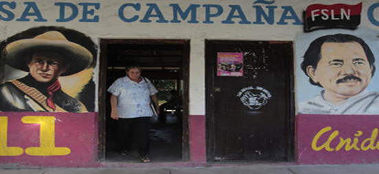 A woman walks past murals of Nicaragua's President Daniel Ortega (r.) and Nicaraguan revolutionary and Sandinista leader Augusto Cesar Sandino in Catarina November 4. President Ortega's ruling Sandinista National Liberation Front party will seek to change the constitution by year-end to remove presidential term limits.