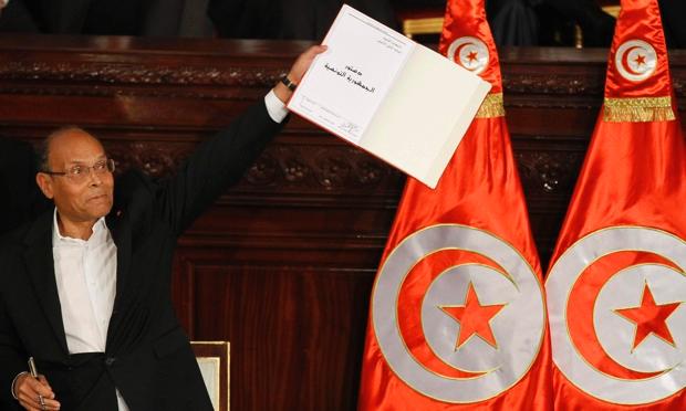 Tunisia's president, Moncef Marzouki, holds a copy of the new constitution after
