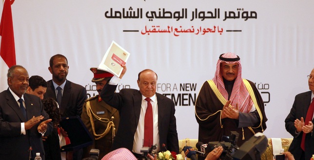Yemen's President Abd Rabbu Mansour Hadi raises the book of recommendations from the country's National Dialogue Conference -- which will guide the drafting of a new constitution and establishment of a federal state.[Mohammed Huwais/AFP]