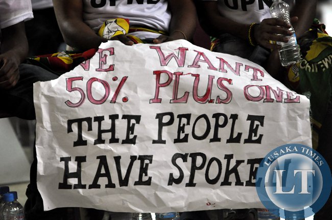 A woman from the UPND displays a placard demanding for the inclusion of the 50 plus one percent clause in the draft Zambian constitution (photo credit: Lusaka Times)